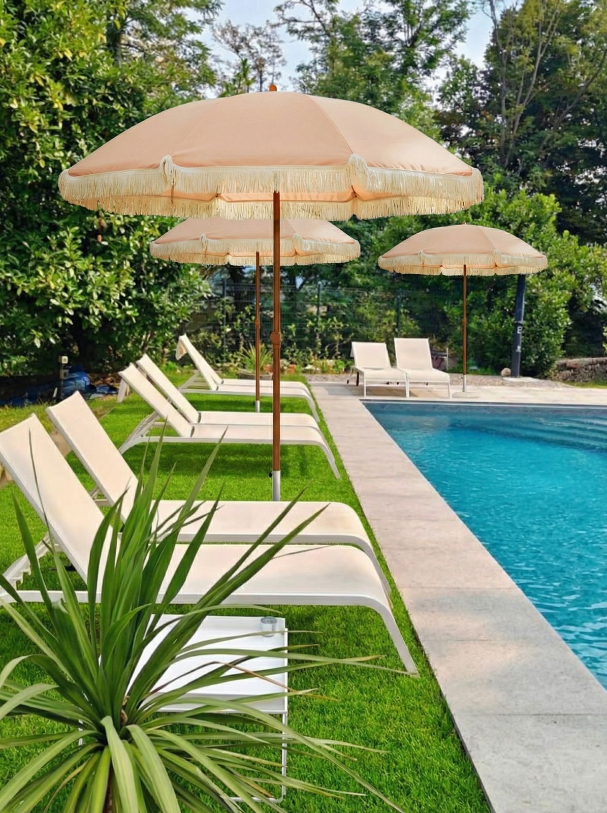 Fringed parasols and sun loungers on the lawn beside the swimming pool in the park
