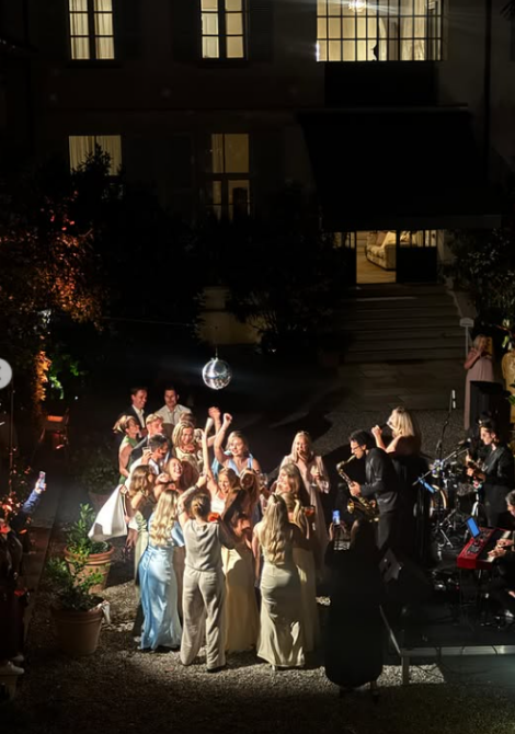 Guests dancing in the courtyard at night under the disco ball, as the band with saxophone plays in front of the lit villa